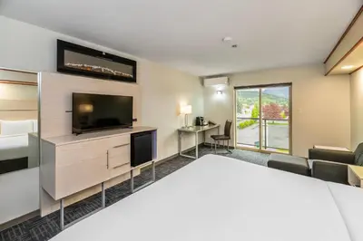 a hotel room with a bed and a flat screen tv at Quality Inn Sunshine Suites in Terrace