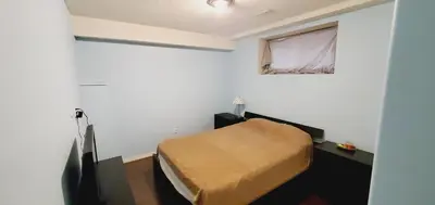 a small bedroom with a bed and a window at Parson Creek Cozy suite in Fort McMurray