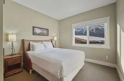 a bedroom with a large bed and a window at Sunset Ridge - Luxurious Corner Condo - Spectacular Mt Views with open Pool! in Canmore