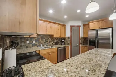 a kitchen with wooden cabinets and stainless steel appliances at Beautiful Peak Vista - 2BR w Stunning Mt Views in Canmore