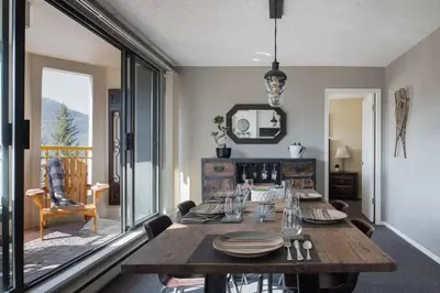 a dining room with a wooden table and a large window at Mountain View Penthouse- 2BR Oasis at the Marquise in Whistler in Whistler