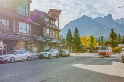 three cars parked in front of a building on a street at Rundle Rise - Spacious Condo Steps from Main Street in Canmore