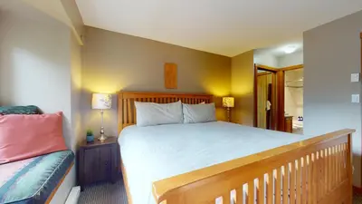 a bedroom with a large bed with a wooden headboard at 2BR in Symphony, Whistler Village, Complex Hot Tub, Gas Fireplace, Parking, Gondola Shuttle in Whistler