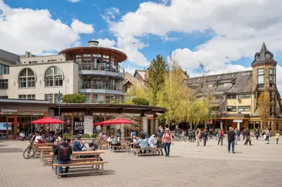 a group of people sitting on benches in a city street at 2BR in Symphony, Whistler Village, Complex Hot Tub, Gas Fireplace, Parking, Gondola Shuttle in Whistler