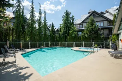a large swimming pool with chairs and a fence at 1BR in Northstar, Village Location, Gas Fireplace, Shared Hot Tub, Ski Storage in Whistler