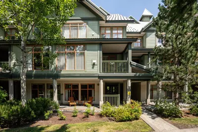 a large green house with a porch at 1BR in Northstar, Village Location, Gas Fireplace, Shared Hot Tub, Ski Storage in Whistler