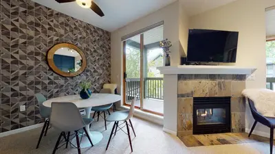 a living room with a table and a fireplace at 2BR in Northstar, Whistler Village, Fireplace, Hot Tub, Central Location, Ski Storage in Whistler