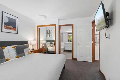 a bedroom with a white bed and a tv at 2BR in The Aspens, Ski In, Ski Out, Pool and Hot Tub, Gas Fireplace, Ski Valet, Gym in Whistler