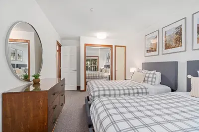 a bedroom with two beds and a mirror at 2BR in The Aspens, Ski In, Ski Out, Pool and Hot Tub, Gas Fireplace, Ski Valet, Gym in Whistler