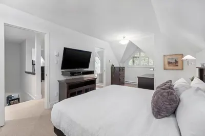 a white bedroom with a bed and a flat screen tv at 3BR in Gleneagle, Soaker Tub with Skylight, Wood Burning Fireplace, Spacious Layout in Whistler