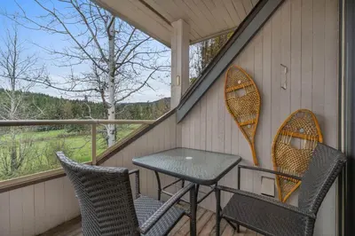 a table and chairs on a porch with two kayaks at 3BR in Gleneagle, Soaker Tub with Skylight, Wood Burning Fireplace, Spacious Layout in Whistler