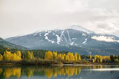 a mountain reflecting in a lake with trees and snow at 3BR Luxury Home in Taluswood, Hot Tub, Ski In, Ski Out, Two-Car Garage, Village Parking in Whistler