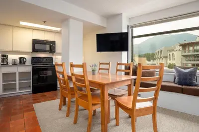 a kitchen and dining room with a wooden table and chairs at 1BR in Carleton Lodge, Unbeatable Mountain Base Location, Ski In, Ski Out, Free Parking in Whistler