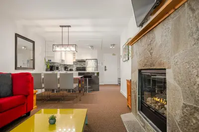 a living room with a red couch and a fireplace at 2BR in Powderhorn, Near Blackcomb, Double-Sided Fireplace, Rooftop Hot Tub, Parking in Whistler