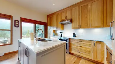a kitchen with wooden cabinets and a counter top at 2BR in Blackcomb Greens, Wood Burning Fireplace, Communal Hot Tub, Nature Views in Whistler