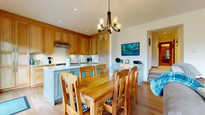 a kitchen and dining room with a wooden table at 2BR in Blackcomb Greens, Wood Burning Fireplace, Communal Hot Tub, Nature Views in Whistler