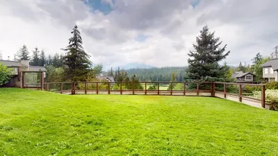 a large yard with a wooden fence and green grass at 2BR in Blackcomb Greens, Wood Burning Fireplace, Communal Hot Tub, Nature Views in Whistler