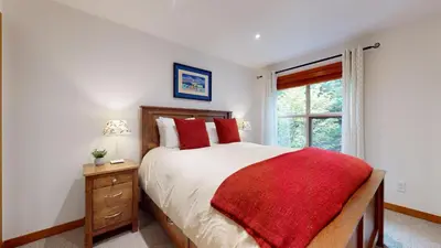 a bedroom with a large bed and a window at 2BR in Blackcomb Greens, Wood Burning Fireplace, Communal Hot Tub, Nature Views in Whistler