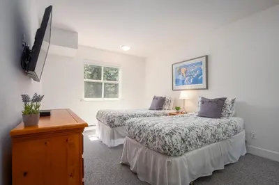 a bedroom with two beds and a tv on the wall at 3BR in Alpine Greens, Soaker Tub, Wood Burning Fireplace, Family Sized in Whistler