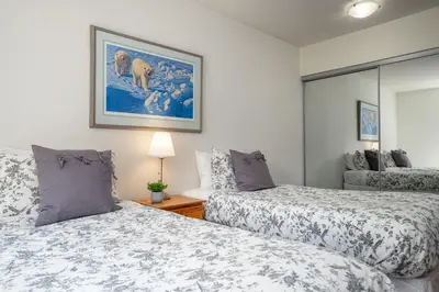 a bedroom with two beds and a painting on the wall at 3BR in Alpine Greens, Soaker Tub, Wood Burning Fireplace, Family Sized in Whistler