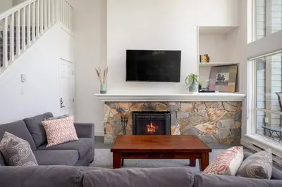 a living room with a fireplace with a tv above it at 3BR in Alpine Greens, Soaker Tub, Wood Burning Fireplace, Family Sized in Whistler