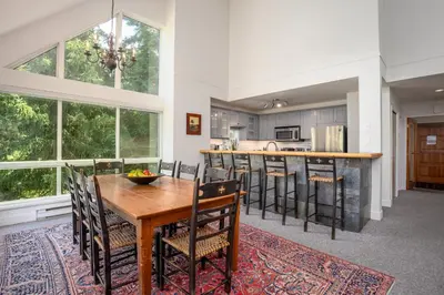 a kitchen and dining room with a wooden table and chairs at 3BR in Alpine Greens, Soaker Tub, Wood Burning Fireplace, Family Sized in Whistler