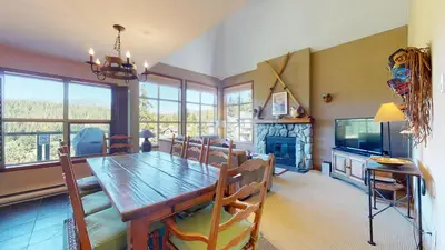 a dining room with a wooden table and a fireplace at 3BR in Blackcomb Greens, Wood Burning Fireplace, Complex Hot Tub, Parking, Mountain Views in Whistler