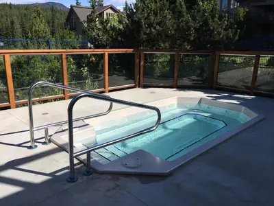 a hot tub on the deck of a house at 3BR in Blackcomb Greens, Wood Burning Fireplace, Complex Hot Tub, Parking, Mountain Views in Whistler