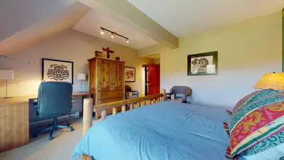 a bedroom with a bed and a desk and a television at 3BR in Blackcomb Greens, Wood Burning Fireplace, Complex Hot Tub, Parking, Mountain Views in Whistler