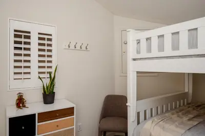 a bedroom with a white bunk bed and a chair at 3BR in Tyndall Stone Lodge, Village Location with Olympic Plaza Views, Fireplace, Hot Tub in Whistler