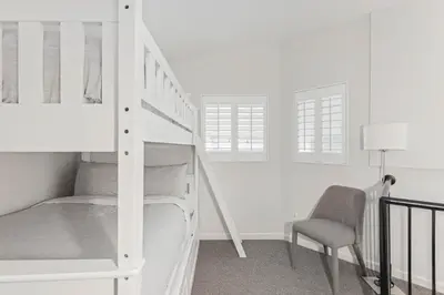 a white bedroom with a bunk bed and a chair at 3BR in Tyndall Stone Lodge, Village Location with Olympic Plaza Views, Fireplace, Hot Tub in Whistler