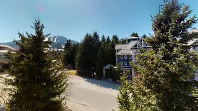 a large blue house with trees in front of it at 1BR plus Loft in Tyndall Stone Lodge, Village Location, Pool and Hot Tub, Private Balcony in Whistler