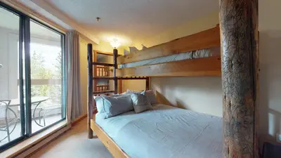 a bedroom with a bunk bed and a large window at 3BR in Greystone Lodge, Ski In, Ski Out, Pool and Hot Tub, Epic Location in Whistler