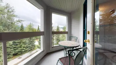 a porch with a table and chairs and windows at 3BR in Greystone Lodge, Ski In, Ski Out, Pool and Hot Tub, Epic Location in Whistler