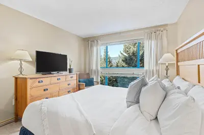 a bedroom with a white bed and a large window at 3BR in Greystone Lodge, Ski In, Ski Out, Pool and Hot Tub, Epic Location in Whistler