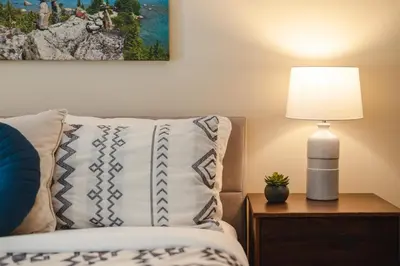 a bed with a pillow and a lamp on a table at 2BR plus Loft in Wildwood Lodge, Free Ski Bus, Hot Tub and Pool, Private Patio, Parking in Whistler