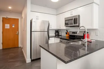 a white kitchen with a stainless steel refrigerator at 2BR plus Loft in Wildwood Lodge, Free Ski Bus, Hot Tub and Pool, Private Patio, Parking in Whistler