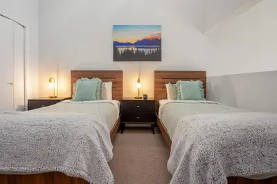 a bedroom with two beds and a painting on the wall at 2BR plus Loft in Wildwood Lodge, Free Ski Bus, Hot Tub and Pool, Private Patio, Parking in Whistler