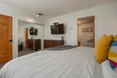 a bedroom with a large bed and a mirror at 2BR plus Loft in Valhalla, Village Location, Covered Patio, King Bed, Hot Tub in Whistler