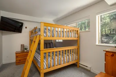 a wooden bunk bed in a room with a television at 2BR plus Loft in Valhalla, Village Location, Covered Patio, King Bed, Hot Tub in Whistler