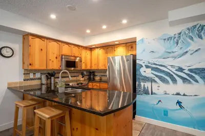 a kitchen with wooden cabinets and a counter top at 2BR plus Loft in Valhalla, Village Location, Covered Patio, King Bed, Hot Tub in Whistler
