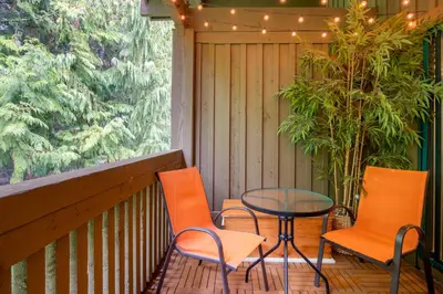 a patio with orange chairs and a table and a window at 3BR in The Woods, Private Hot Tub, Wood Burning Fireplace, King Ensuite, Private Garage in Whistler