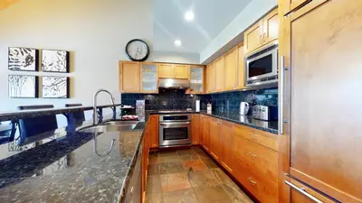 a kitchen with wooden cabinets and a clock on the wall at 3BR in Montbello, Cozy Townhouse, Private Hot Tub, Near Village, Fireplace in Whistler