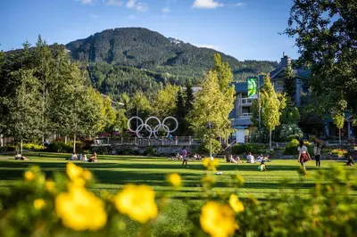 a park with people sitting in the grass with the olympic rings at 3BR in Lagoons, King Bed, Private Balcony, Village Location, Parking in Whistler