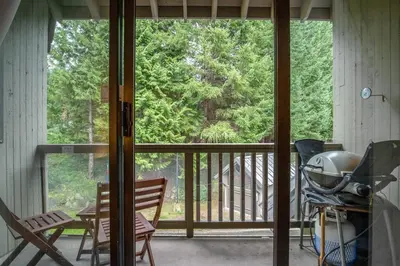 a screened in porch with a view of the woods at 2BR plus Den in The Gables, Dog Friendly, Near Both Mountains, Wood Burning Fireplace, Free Parking in Whistler