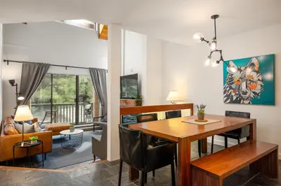 a dining room and living room with a table and chairs at 2BR plus Den in The Gables, Dog Friendly, Near Both Mountains, Wood Burning Fireplace, Free Parking in Whistler