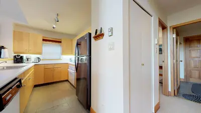 a kitchen with wooden cabinets and a stainless steel refrigerator at 3BR in Alpine Greens, Ski Storage, Wood Burning Fireplace, Free Ski Shuttle in Whistler