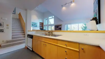 a kitchen with a sink and a staircase at 3BR in Alpine Greens, Ski Storage, Wood Burning Fireplace, Free Ski Shuttle in Whistler