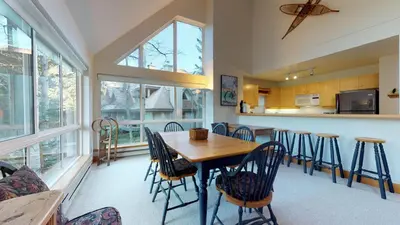 a kitchen and dining room with a wooden table and chairs at 3BR in Alpine Greens, Ski Storage, Wood Burning Fireplace, Free Ski Shuttle in Whistler
