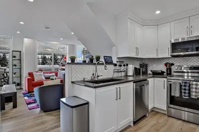 a kitchen with white cabinets and a living room at The Parq by Samsara Resort Top View Downtown 4BR & 3BTH in Canmore